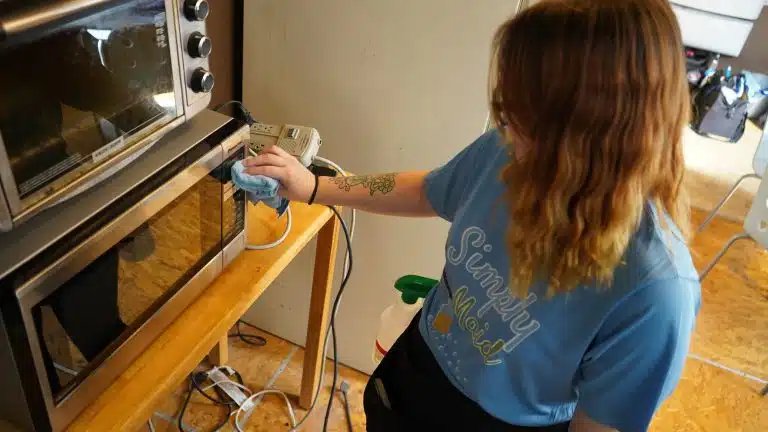 Simply Maid Sparkle Technician spraying and wiping a mirror