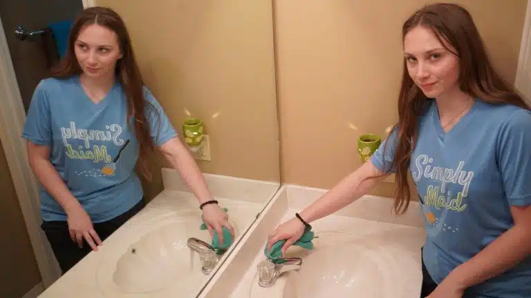 Two smiling Simply Maid Sparkle Technicians cleaning double bathroom sinks